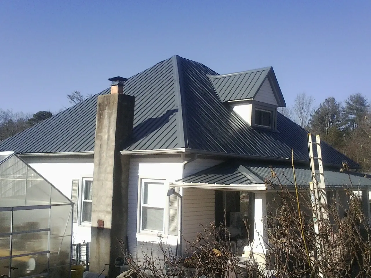 Dark blue standing seam metal roof on a white farmhouse with dormer — Slate & Tile Roof Repair by Roofing Brothers in Woolwich