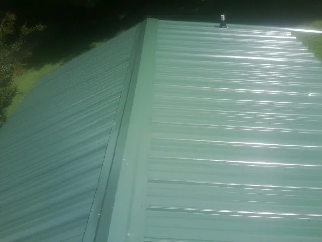 New green metal panels meeting at the ridge of a roof — Flat Roof Repair work by our crew in Woolwich