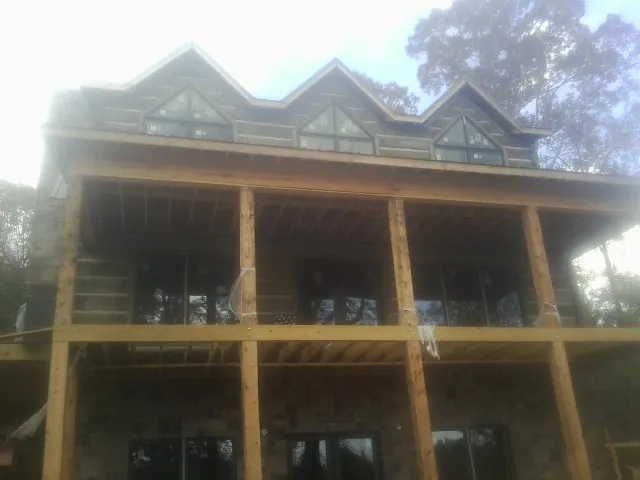 Dormers and porch framing on a large log home under construction — Roof Coating work by our crew in Woolwich