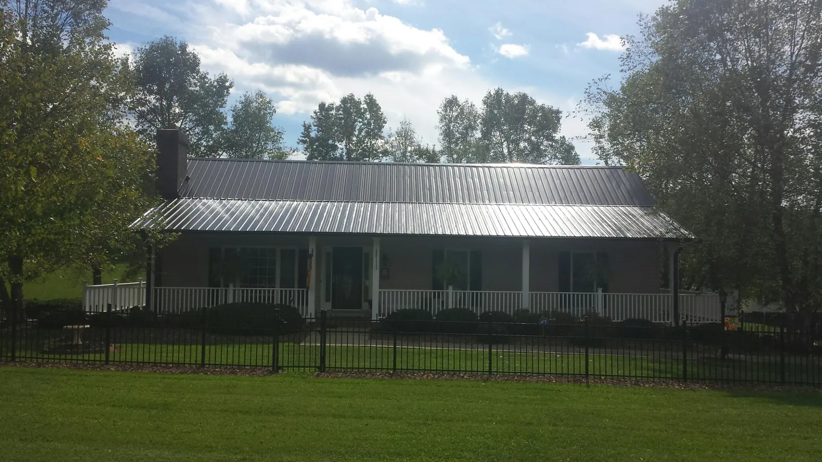 Gray metal roof on a brick ranch with a full width front porch — Gutter Guard Installation work by our crew in Woolwich