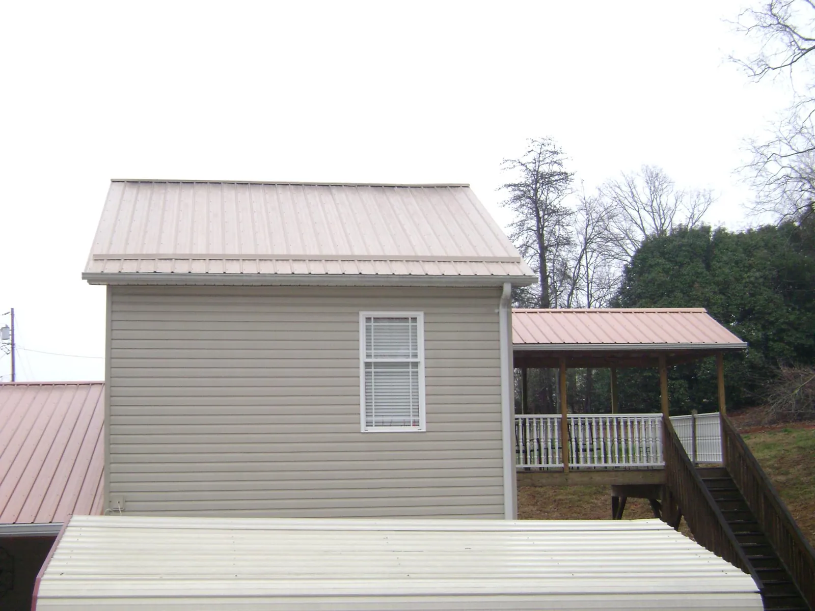 Tan metal roofs on a two story addition and attached porch, from a Roof Replacement job in Woolwich
