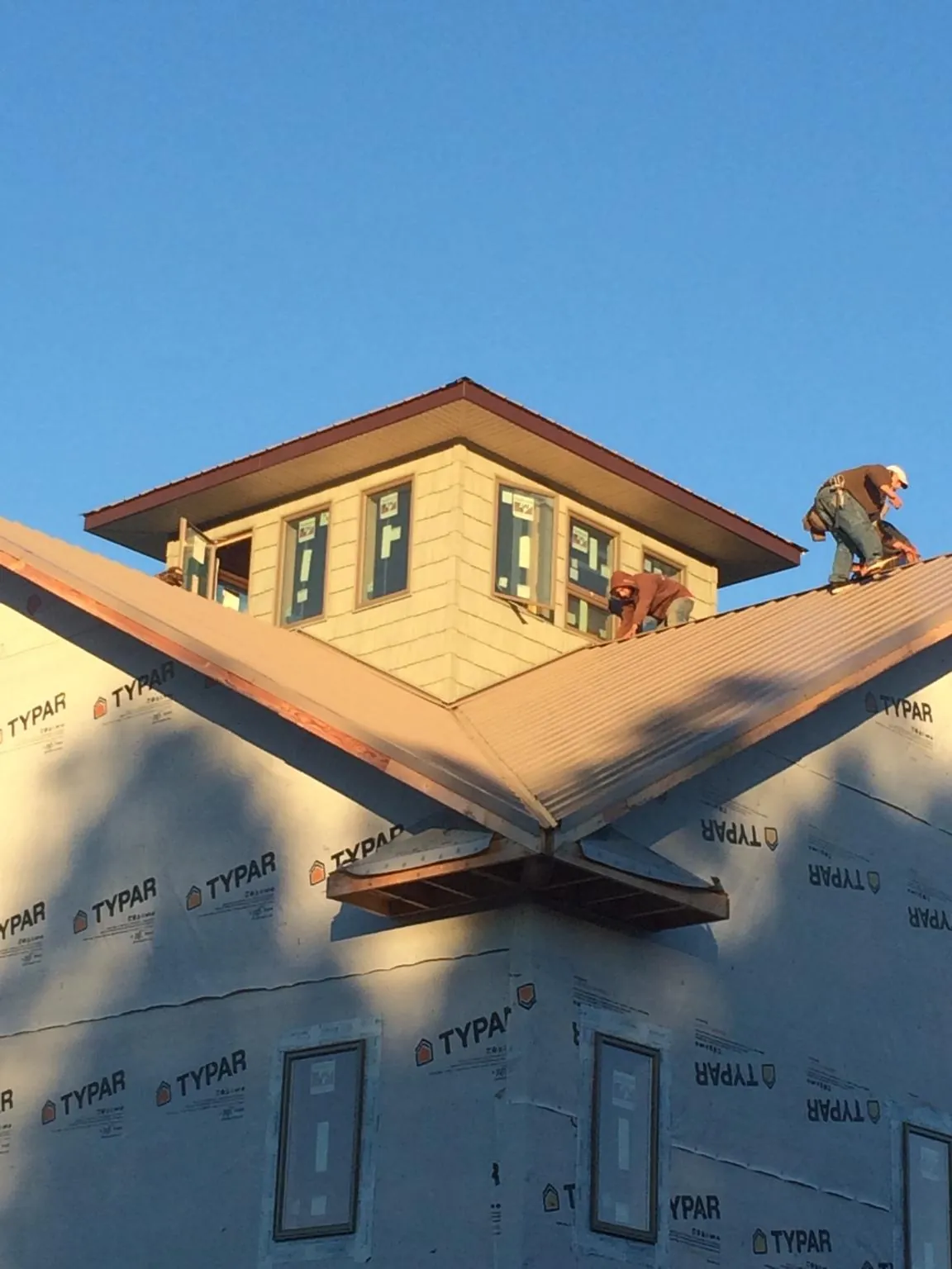 Roofers working around a rooftop cupola on a new metal roof at sunset — Roof Waterproofing in Woolwich by Roofing Brothers